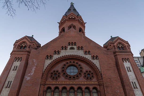 Low angle view of the ornate brick facade and tower of Passionskirche church in Berlin against an evening sky.