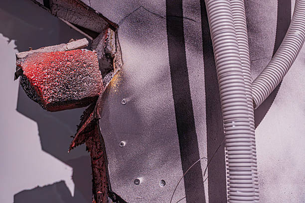Close-up view of corroded metal object with rust, chipping paint, irregularities, vertical ridges or pipes, earth tone color palette, strong directional light from above, texture focus, potential aba