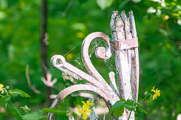 istock An outdoor scene features a weathered, possibly wrought iron, sculpture or decorative piece with scrollwork Set against green foliage and trees, the sculpture is positioned at an angle, suggestive o 2214009416
