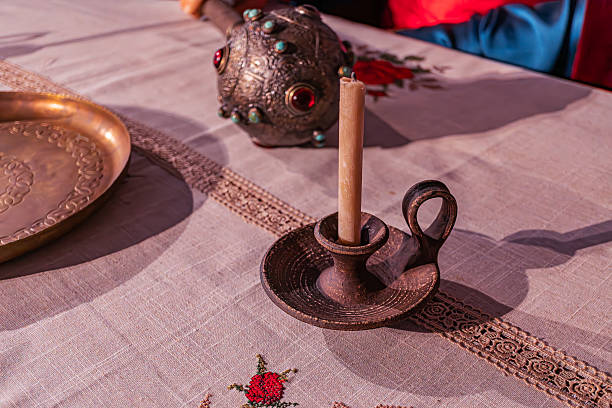 istock Indoor scene with a table and objects, including a golden bowl covered by a patterned fabric reds, blues, a floral metal lamplantern metal, floral design, handle, candles, and a single white can 2214009703