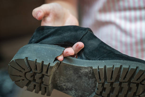 istock hand points through a hole in a worn-out shoe, highlighting the damage. The image captures the innocence of childhood and the realities of playtime wear and tear 2214013528
