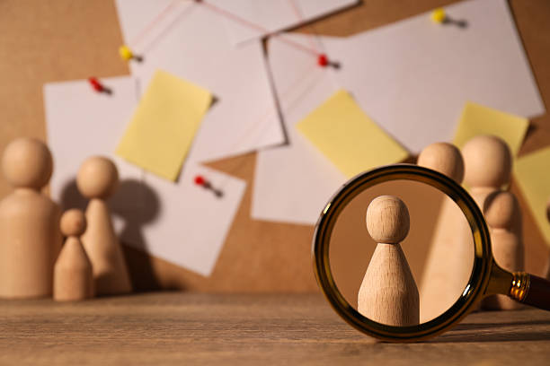 istock A wooden figurine under a magnifying glass 2214017529