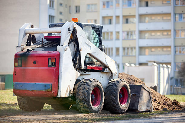 Old dirty rusty mini bulldozer digger near road over urban background with copyspace selective focus three quarter back view