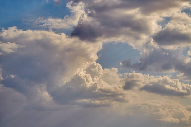Light streams through cumulus clouds in the sky close-up, cloudy weather, light on clouds.