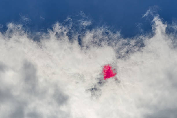 A small heart rests on fluffy clouds against a deep blue sky. Suitable for romantic backdrops.