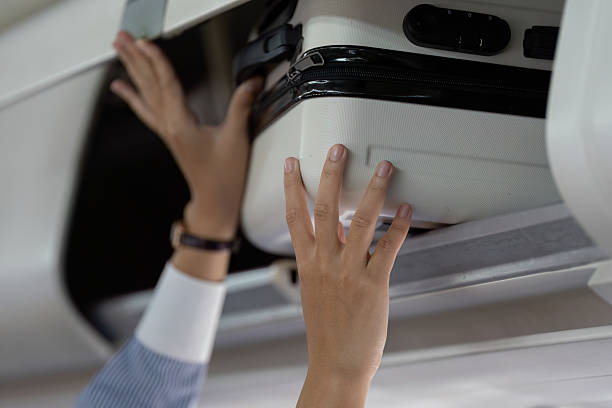 Business travel: passenger placing luggage in overhead compartment
