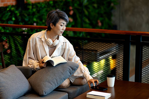 istock elder 50+ woman sitting  relax read book on sofa i 2214021579