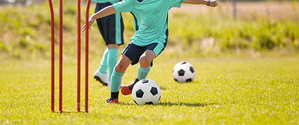 istock Young Soccer Player Practicing Dribbling Skills Through Training Poles on a Grass Field 2214021740