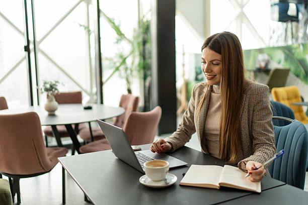 istock Businesswoman working on laptop and taking notes in a cafe 2214021815
