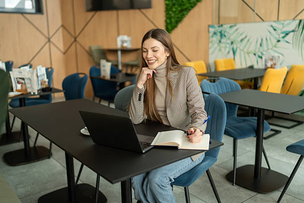 istock Young businesswoman taking notes while working on a laptop in a cafe 2214021899