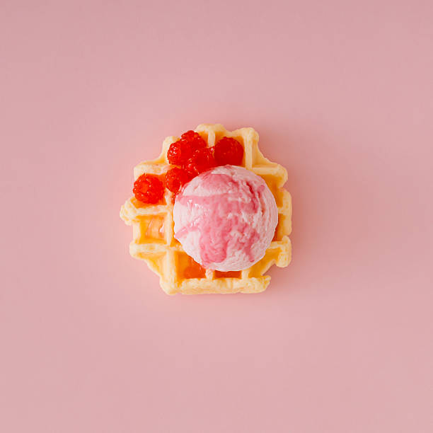 Waffle and pink ice cream with raspberry topping and fresh red berries on pastel pink background. Minimal sweet food concept. Trendy delicious dessert idea. Flat lay style.
