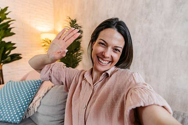 istock Young Woman Taking Selfies While Sitting On The Sofa At Home 2214022412