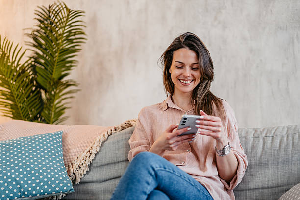 istock Young Woman Texting On The Phone While Sitting On The Sofa At Home 2214022634