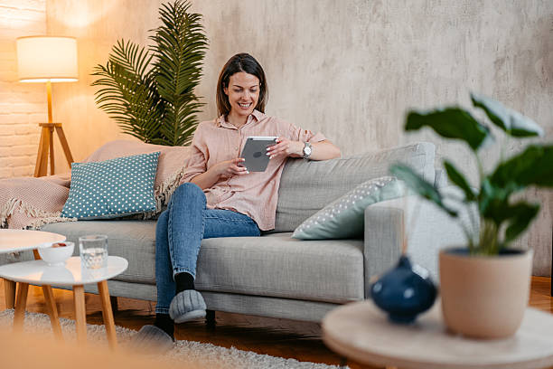 istock Young Woman Using Digital Tablet While Sitting On The Sofa At Home 2214022644