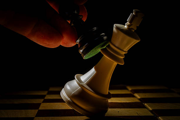 istock Black pawn knocking down white king on chessboard 2214023209