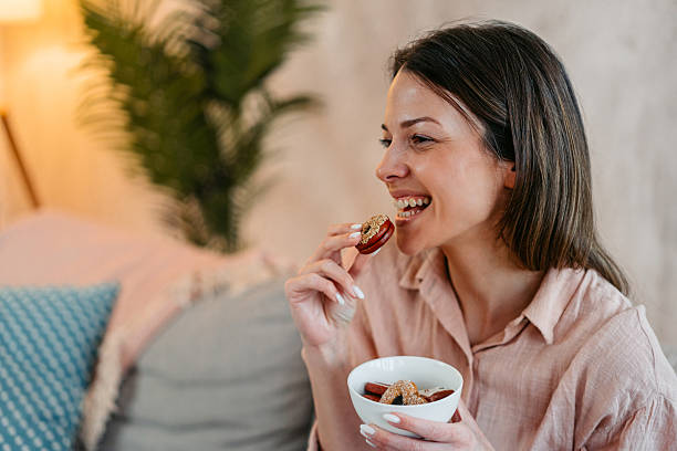 istock Young Woman Eating Cookies While Sitting On The Sofa 2214023952