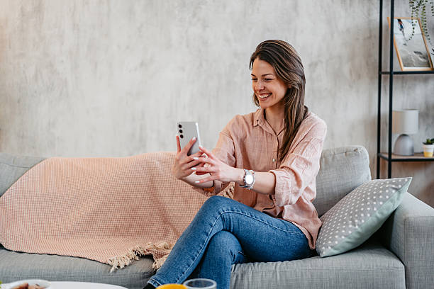 istock Young Woman Taking Selfies Using Phone While Sitting On The Sofa At Home 2214024156