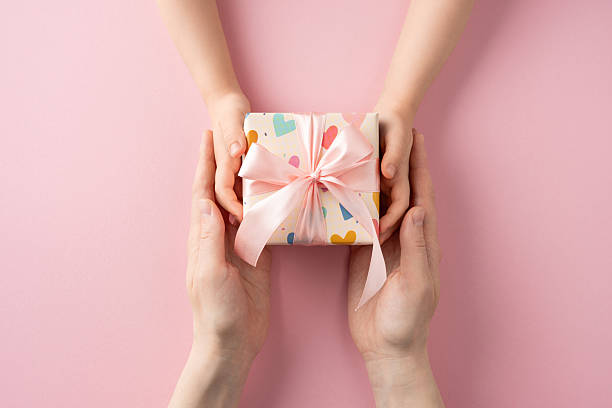 istock Representation of joy and care through a wrapped gift being exchanged hands 2214025573