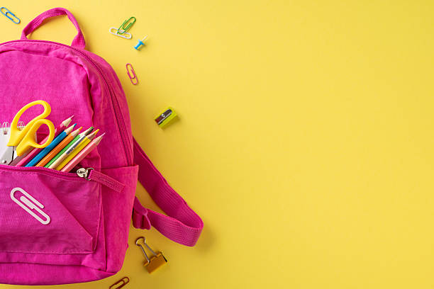 istock A vibrant pink backpack filled with colorful school supplies lying on a yellow backdrop 2214025621
