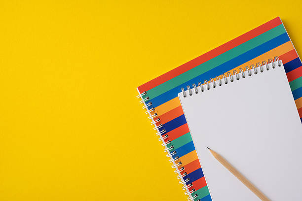 istock Spiral-bound notebooks with patterns and a pencil on a vibrant yellow background creating a cheerful and educational feel 2214025625
