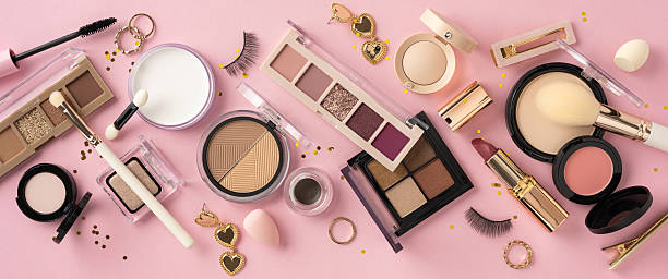 istock Flat lay of makeup essentials including palettes, brushes, and accessories on a stylized pink surface 2214025669