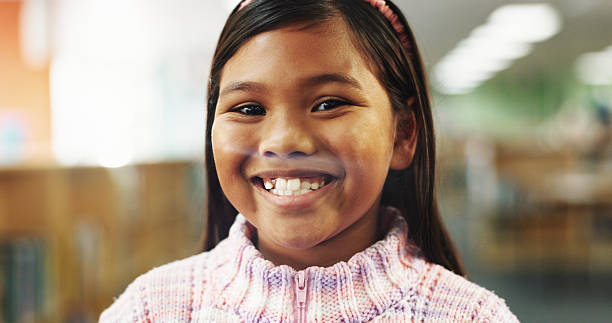 Excited, education and portrait of child in library for learning, studying or development with literature. Happy, face and student with back to school, scholarship or growth at campus.