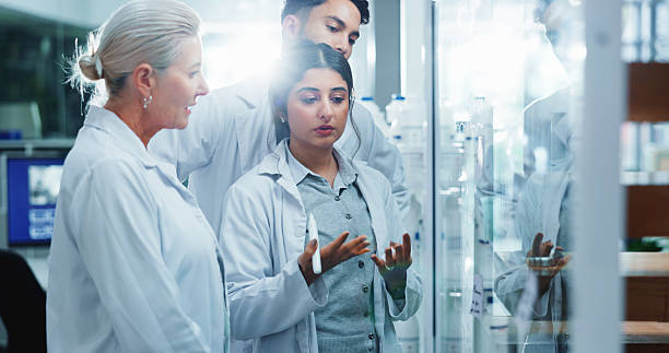 istock Glass wall, brainstorming and people in lab, research and collaboration for experiment. Science, group and employees in workplace, cooperation and review chemistry equation with medical results 2214027437