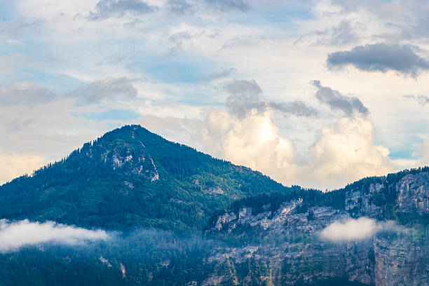 Mountain landscape mountains green fields forest clouds and blue sky in the Alps Vorarlberg Austria.