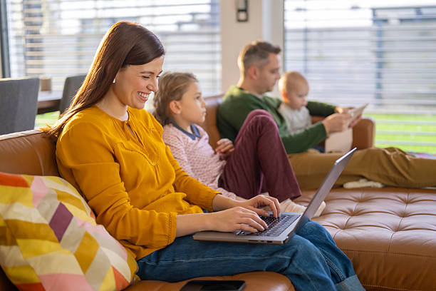 istock Young Family Relaxing On Brown Leather Couch While Using Digital Devices At Home 2214027848