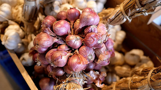 A wooden crate filled with red onions and garlic