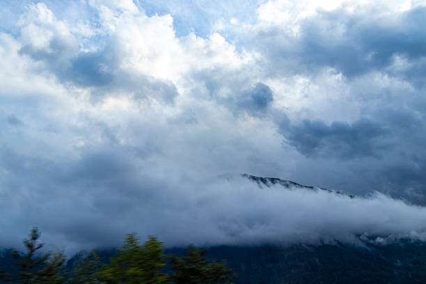 Mountain landscape mountains green fields forest clouds and blue sky in the Alps Vorarlberg Austria.
