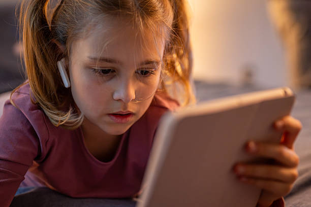 istock Young Caucasian Girl Using Digital Tablet in Cozy Bedroom with Warm Lighting 2214033761