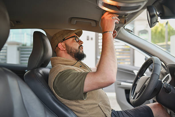 istock Driver Opening Sun Visor to Use Vanity Mirror in Moment of Self-Check 2214036524
