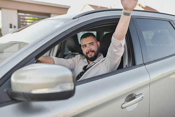 istock Happy Male Greeting Neighbor With Wave While Driving Car With Open Window 2214036548