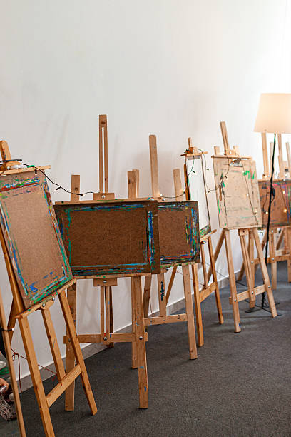 istock Empty wooden easels in an art studio lined up against a white wall 2214037338
