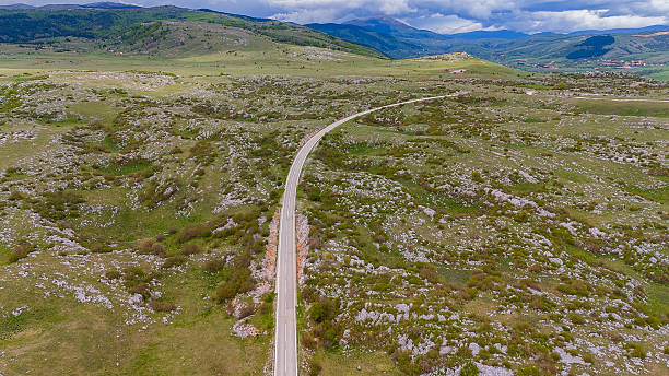 istock Asphalt road through the karst landscape with pastures and rock formations in springtime 2214038147
