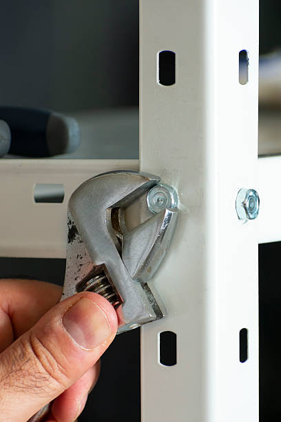 istock Man Fixing Metal Shelves with Wrench 2214039452
