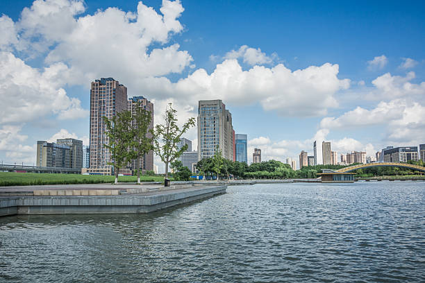 istock Serene Lakeside View with Modern Skyline and Lush Greenery Under Bright Sky 2214041669