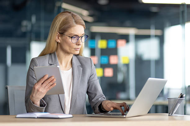 istock Businesswoman multitasking with laptop and tablet at her office desk during work hours. 2214042867