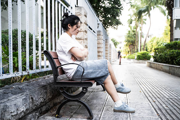 A girl is sitting on a chair in the park.