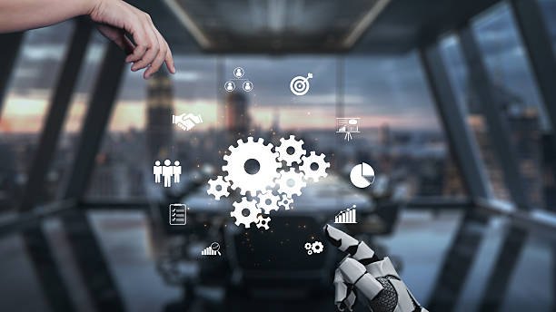 istock Futuristic Office Environment with Human Hands and Robotic Arm Interacting with Digital Business Icons and Graphs in a Modern Workspace Setting. Auvana 2214045917