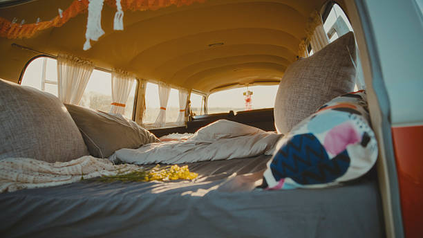 Sunlight Streams into a Campervan,Illuminating a Bed Made up with Pillows and Blankets,Creating a Cozy and Inviting Atmosphere for a Relaxing Road Trip