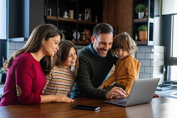 istock Parents and child relaxing at home with computer watching funny internet video, making online call 2214046819