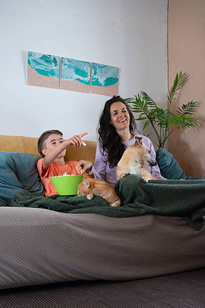 istock Family watching tv with pets and eating popcorn on sofa 2214048712