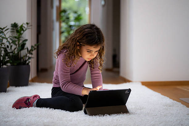 istock Curious Girl Using Tablet Alone on Carpet at Home 2214049530