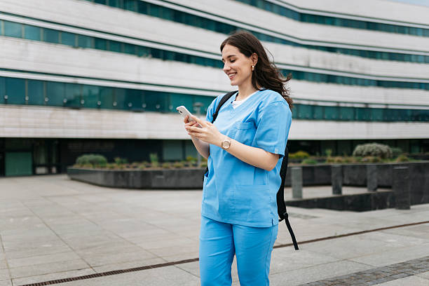 istock Smiling nurse using smartphone outside hospital building 2214052336