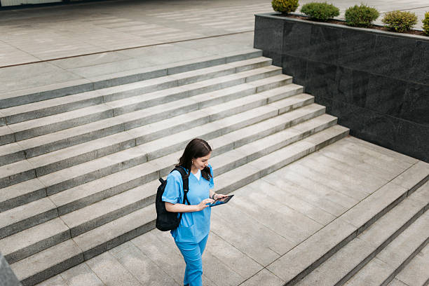 istock Young nurse walking down hospital stairs and using digital tablet 2214052724