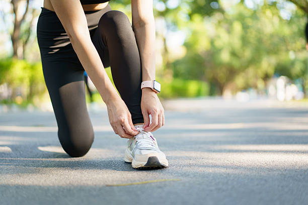 istock Woman tie a shoelace while running in the park. 2214054476