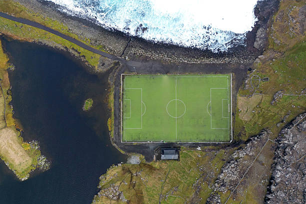 Aerial view of a soccer field surrounded by lake and ocean just outside the small village of Eidi on the north-west tip of Eysturoy on Faroe Islands.
