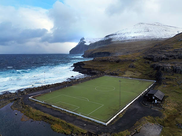 dramatic island emerges from the tranquil waters of the Faroe Islands, shrouded in a thick layer of fog